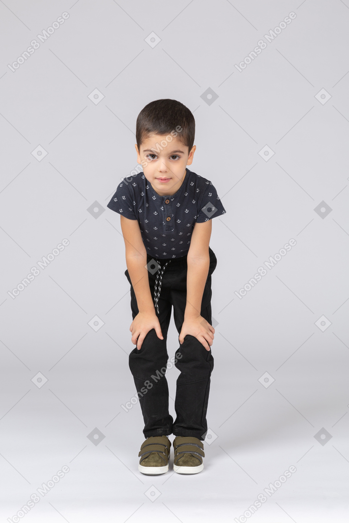 Front view of a cute boy squatting and touching knees