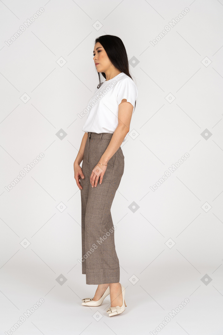 Three-quarter view of a serious young lady in breeches and t-shirt standing still