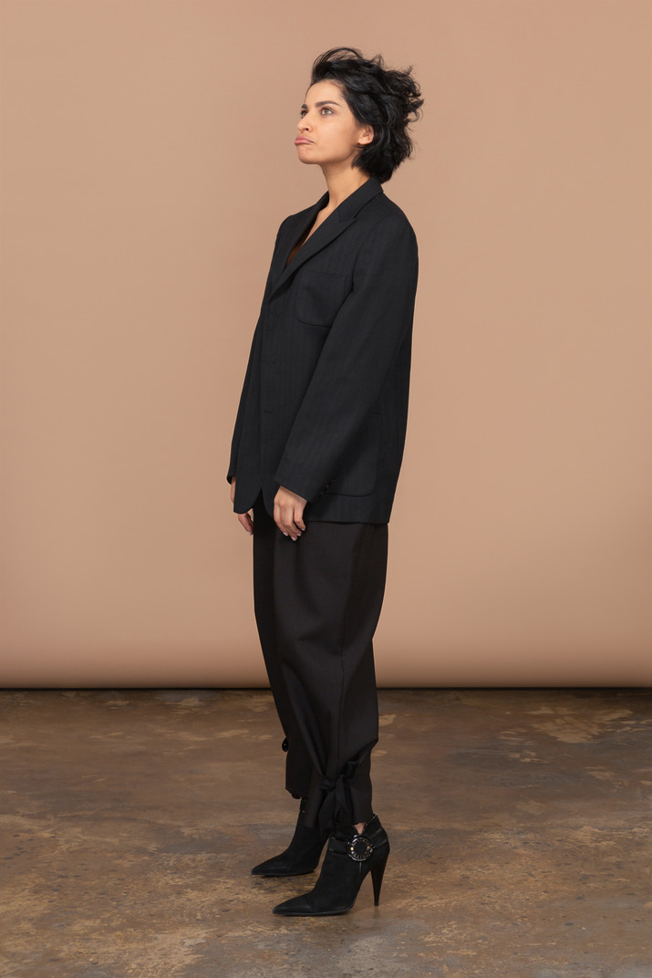 Three-quarter view of a pouting businesswoman in a black suit looking up sadly