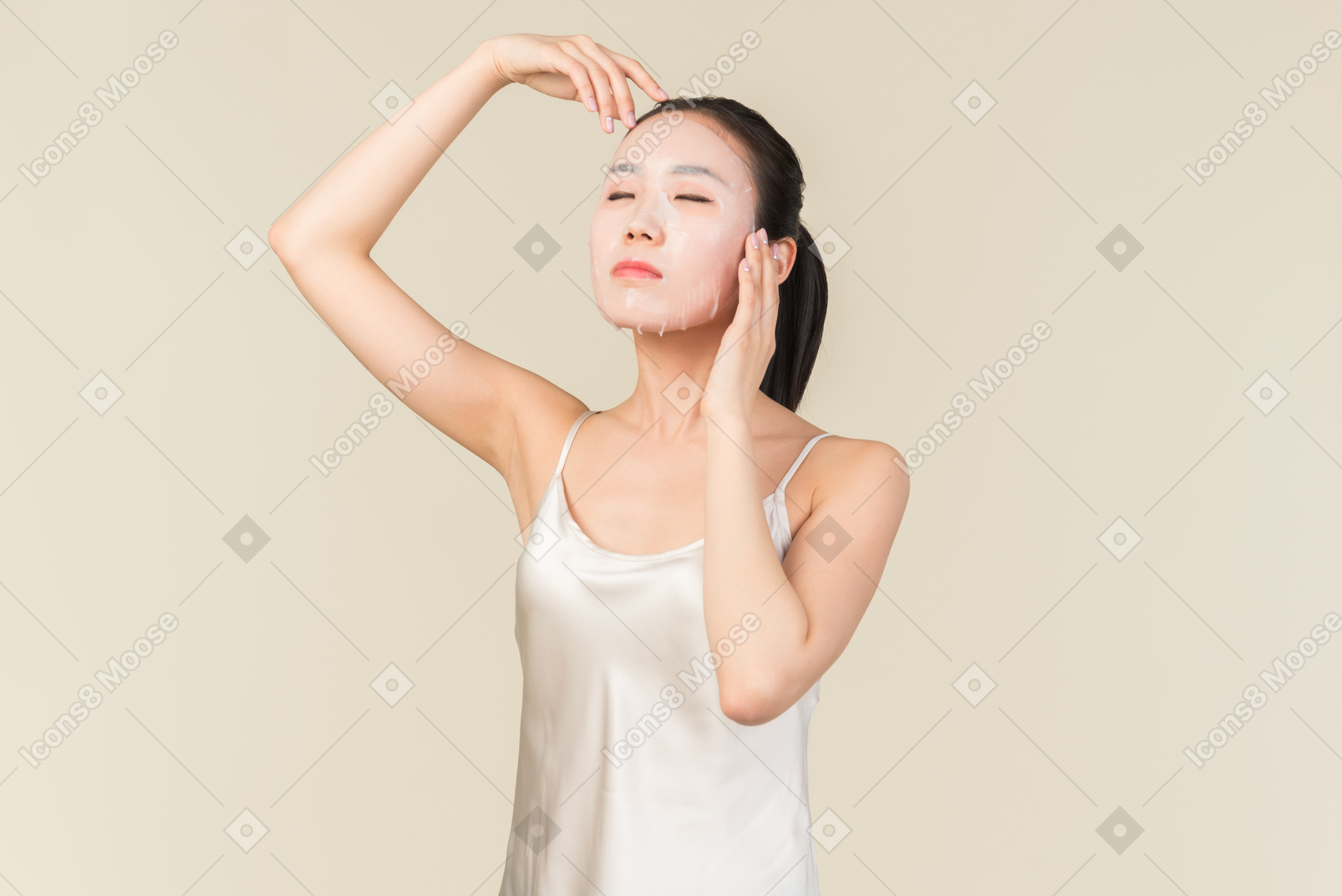 Расслабленная молодая азиатская женщина с лицевой маской, касающейся головы