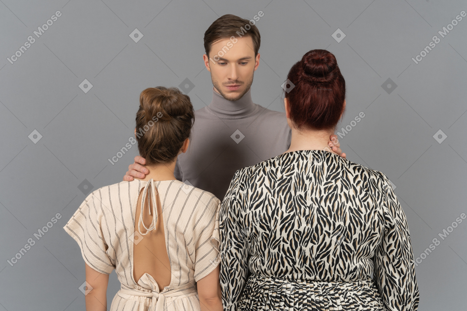 Young man touching necks of two women in front of him