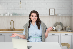 A woman sitting at a table with laptop and holding a credit card