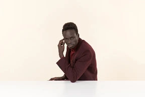 Elegante hombre negro sentado a la mesa en la oficina