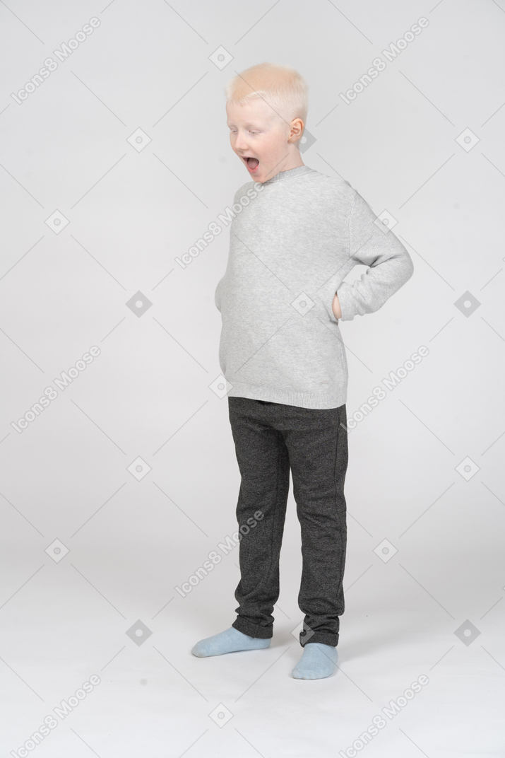 Vista di tre quarti di un bambino che urla mentre mette le mani sui fianchi
