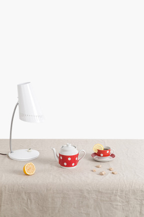 Bodegón con juego de té de lunares, lámpara de escritorio y limones