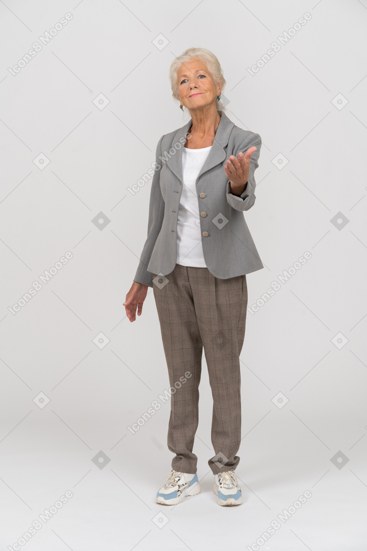 Vue de face d'une vieille dame en costume faisant un geste de bienvenue