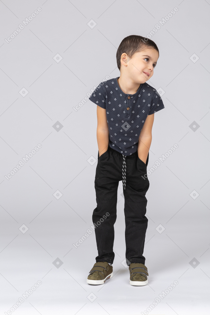 Vista frontal de um lindo menino posando com as mãos nos bolsos