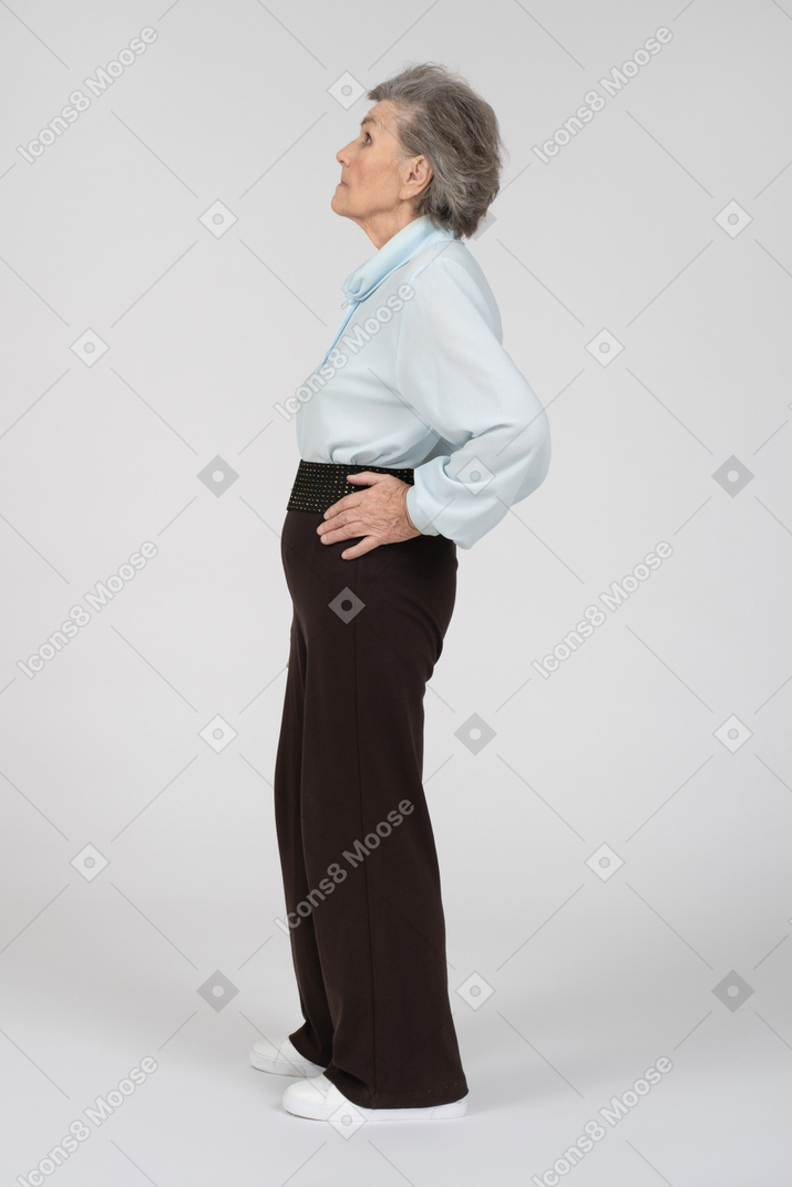一位老妇人的侧视图，手放在臀部期待地抬头