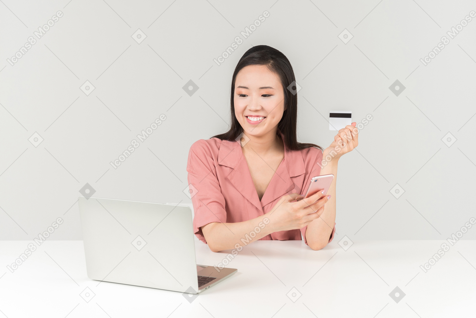 Smiling young asian woman holding bank card while doing online shopping