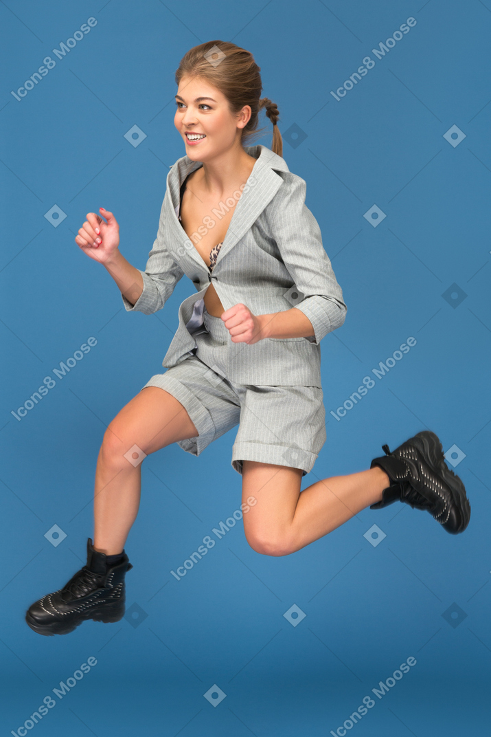 Smiling young woman jumping sideways