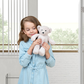 A little girl holding a white teddy bear