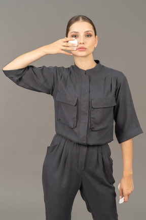 Front view of a young woman in a jumpsuit removing make-up