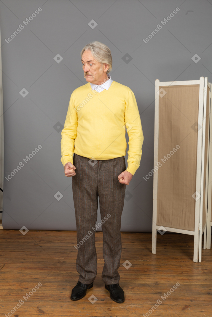 Front view of a strong old man clenching fists while looking aside