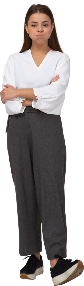 Vista frontal de uma jovem com roupa de escritório soprando bochechas e cruzando os braços