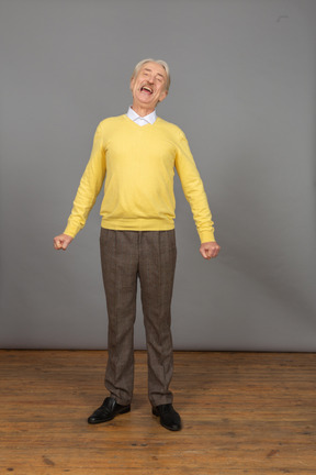 Front view of a yawning man in a yellow pullover standing still and looking at camera
