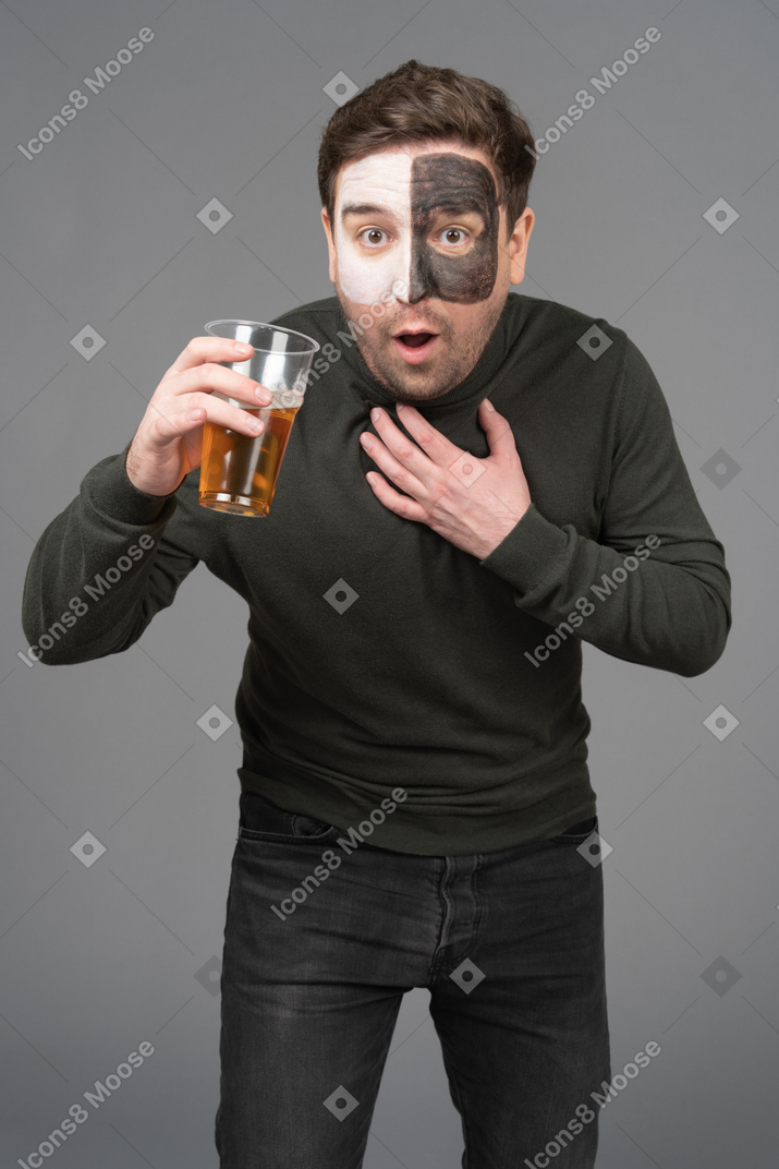 Front view of a surprised male football fan holding a beer and leaning forward
