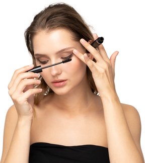 Front view of a young woman wearing black top applying mascara