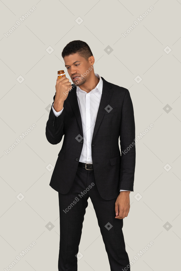 African american man in black suit looking at pills bottle he's holding