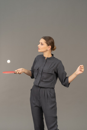 Front view of young woman in a jumpsuit playing table tennis