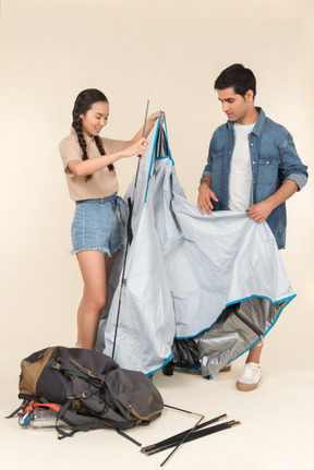 Joven mujer asiática y hombre caucásico construyendo una carpa