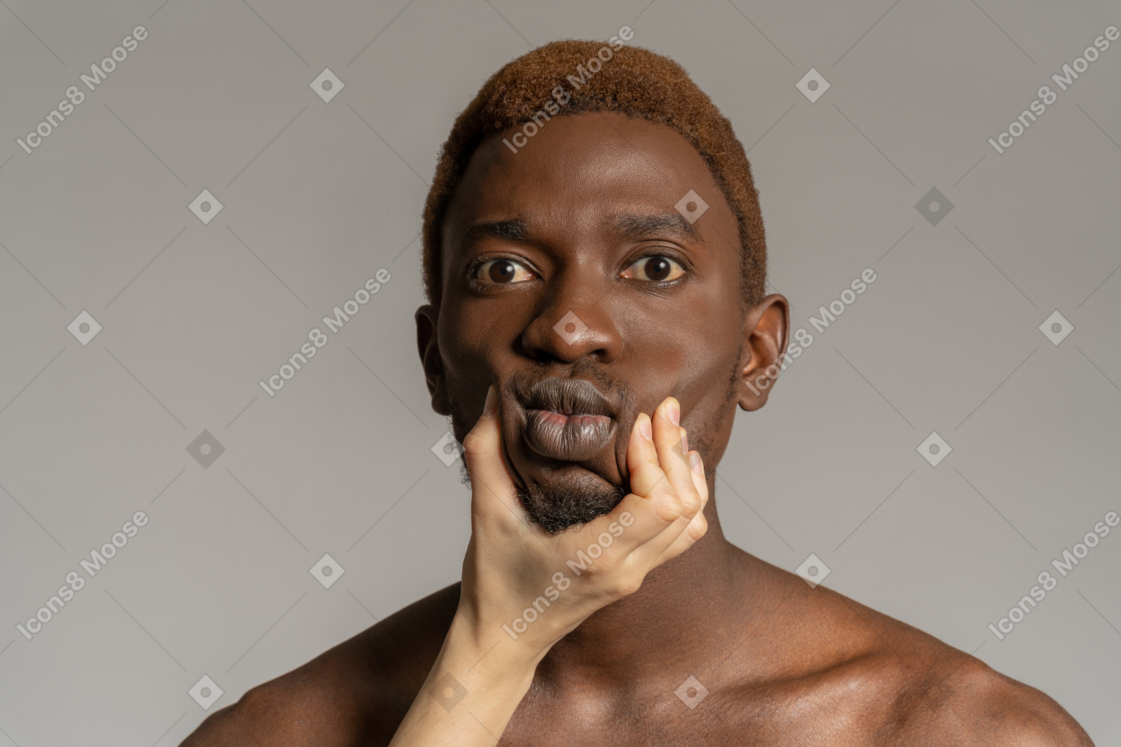 Main blanche touchant le visage d'un jeune homme noir