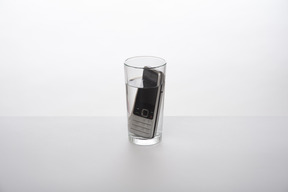 Telefone celular em um copo de água