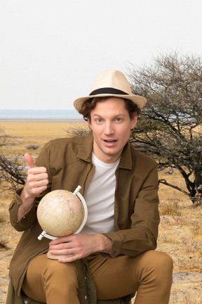 A man in a hat is holding a globe