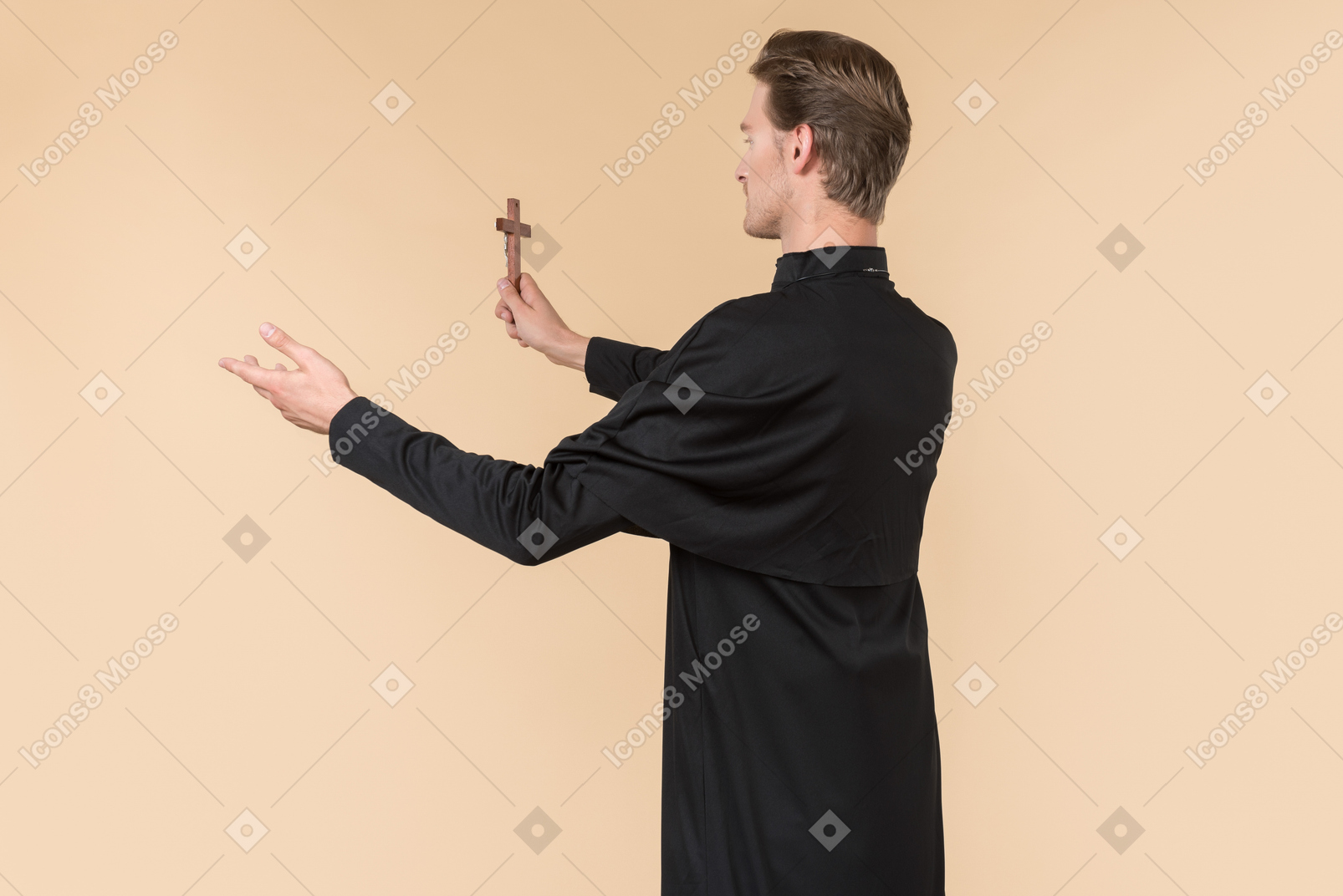 Catholic priest standing half sideways back to camera and holding cross