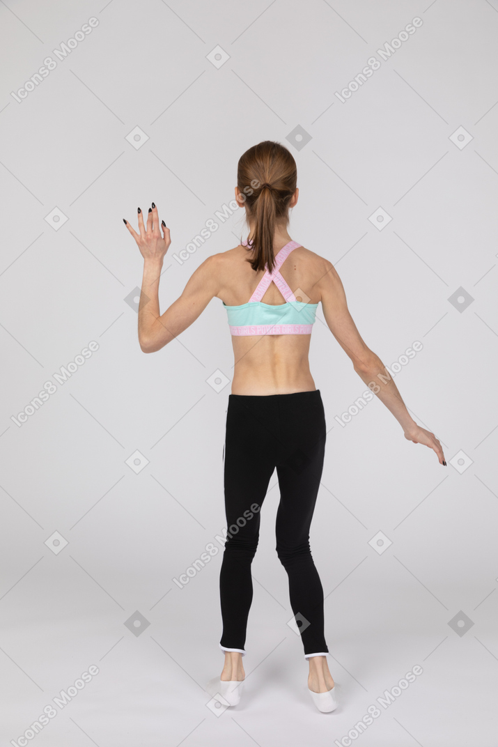 Rückansicht eines jugendlich mädchens in der sportbekleidung, die hand springt und winkt