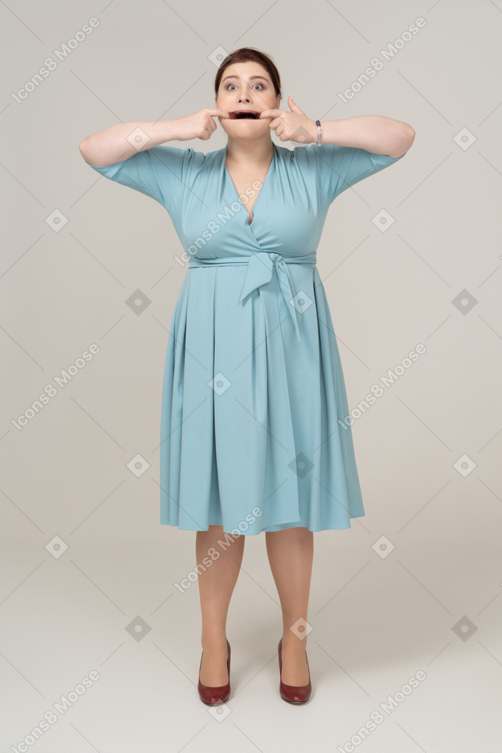 Front view of a woman in blue dress touching her mouth