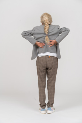 一位身着西装、背部疼痛的老妇人的后视图