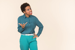 Black woman with a short haircut, wearing all blue, standing against a plain pastel background, looking emotional