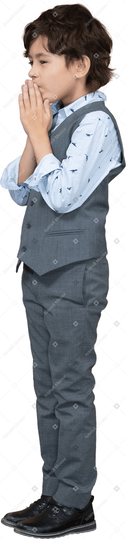 祈りのジェスチャーを作る灰色のスーツを着た少年の側面図