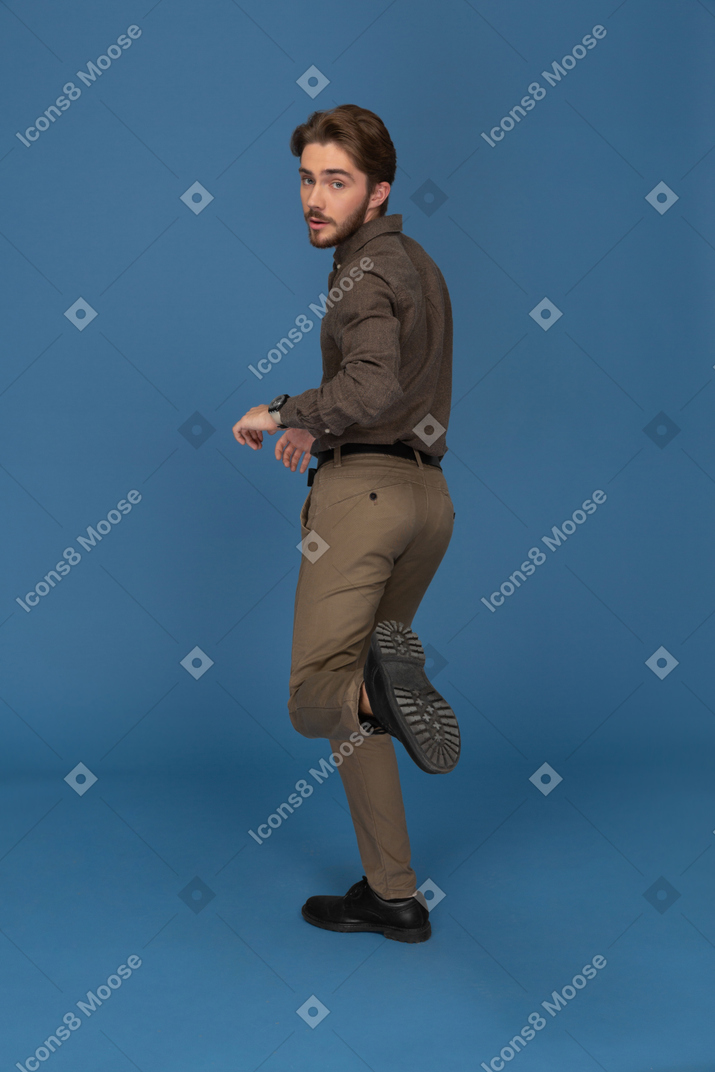 A slim young man raising one foot