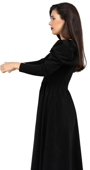Vue latérale d'une jeune femme dans une robe noire qui tend les mains