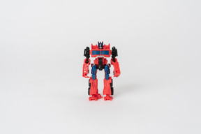 A toy transformer figure of red and black colours standing against a plain white background