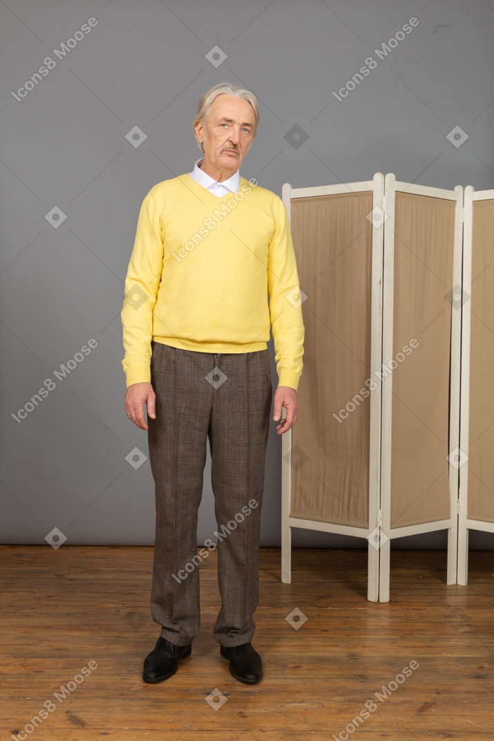 Front view of a moody old man standing still