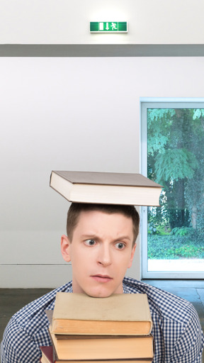 A confused man with his head in between books