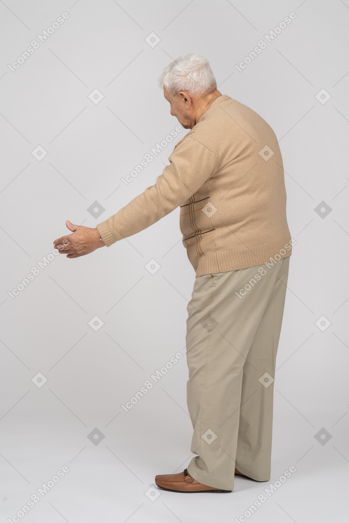 Vista lateral de um velho em roupas casuais, dando uma mão para apertar