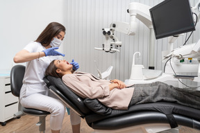 Full-length of a female dentist examining her patient with a mirror