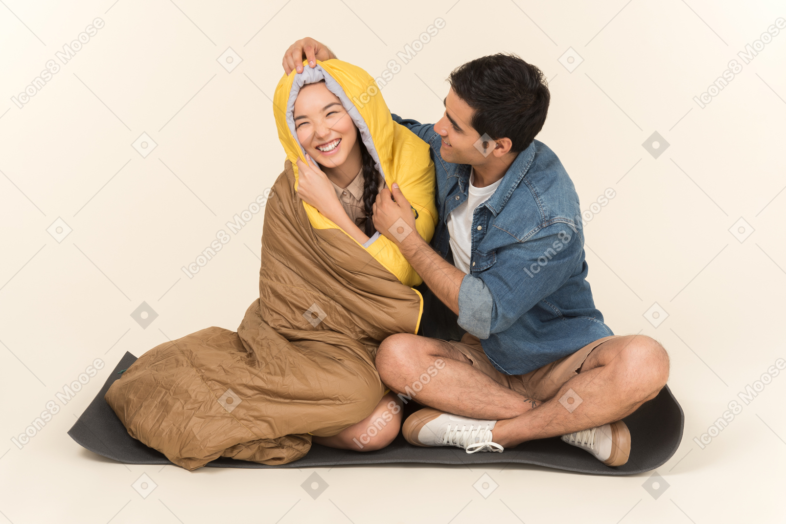 Young interracial couple sitting in sleeping bags and fooling around