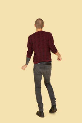 Back view of a dancing young man dressed in red pullover
