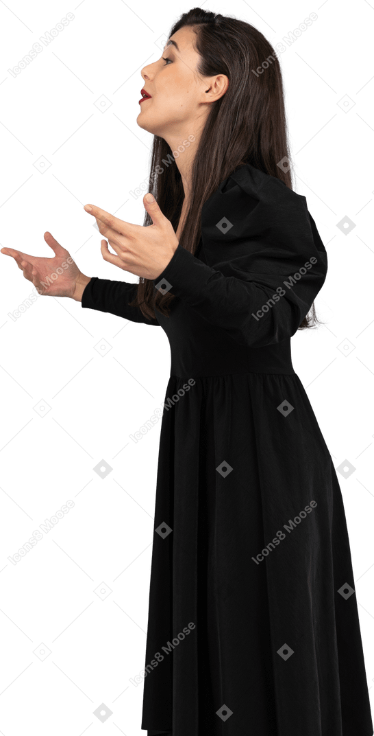 Вид сбоку жестикулирующей молодой женщины в черном платье
