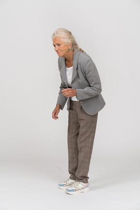 一位身穿灰色夹克的老妇人弯下腰的侧视图