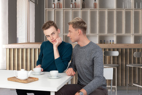 Two men sitting at a table with cups of coffee