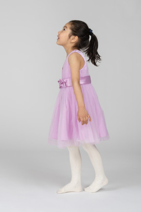 見上げるピンクのドレスを着た女の子の側面図