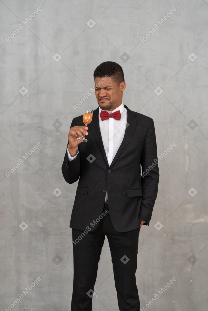 Uomo ribellato in abiti formali in piedi con un bicchiere di champagne