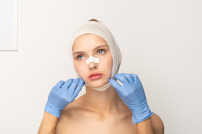 Young woman with bandaged head and hands touching her face