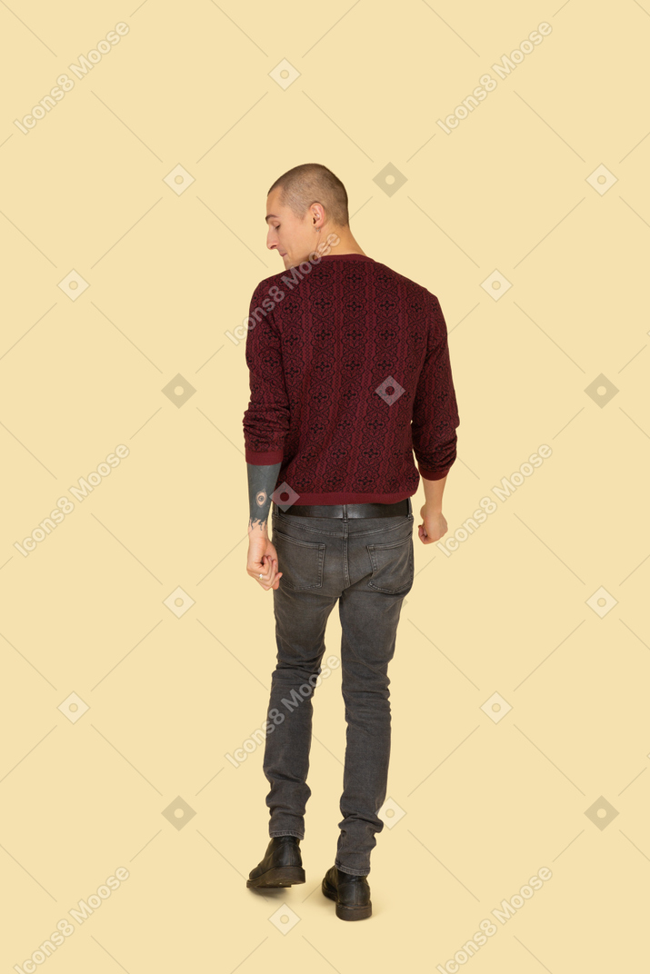 Back view of a young man in red pullover pressing lips