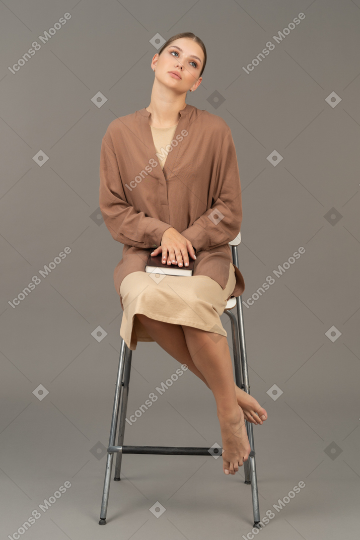 Young woman looking aside while sitting with the book